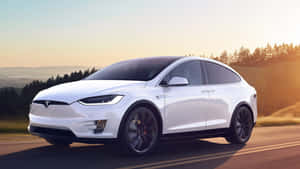 白色Tesla Model X在日落時分行駛在風景優美的道路上。