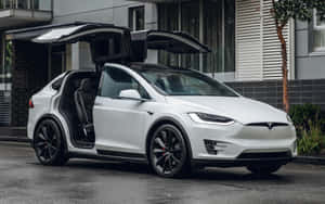 白色Tesla Model X，打開鷹翼門，停泊在濕潤街道上。