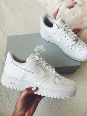 手拿著白色Nike Air Force 1運動鞋及原裝鞋盒。