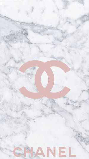 白色大理石背景上的粉紅色Chanel標誌和文字。