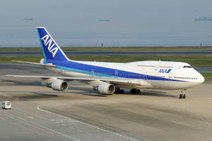 ANA波音747飛機在機場跑道滑行，靠近海洋。
