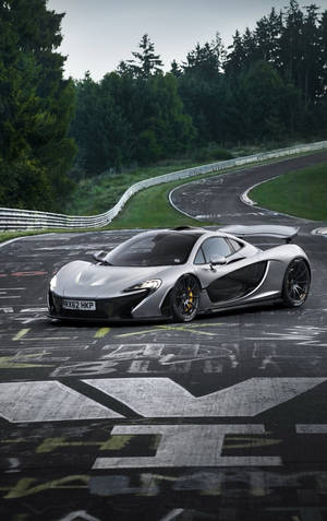 銀色McLaren P1在茂密森林環繞的彎曲賽道上飛馳。