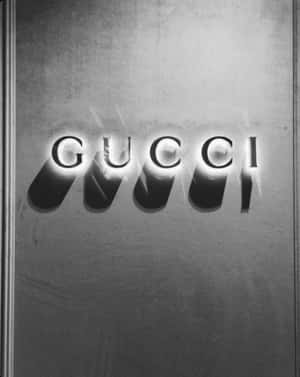 Gucci 標誌喺有紋理嘅金屬背景上發光。