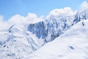 晴朗藍天與零星白雲下的雪山山脈。 — MacBook Pro M3 壁紙