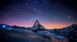 帶有紫色和橙色色調的星空暮色天空下的白雪覆蓋山峰。 — 月色夜空 壁紙