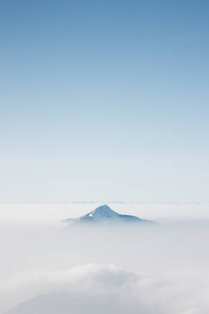白雪覆蓋的山峰在清澈的藍天下從雲層中浮現 — 藍天 壁紙