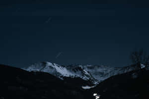 白雪覆蓋的山脈，在繁星點點的夜空下，可見星軌。 — MacBook Pro 14 壁紙