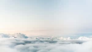 在柔和天空下，從雲海中浮現的白雪覆蓋的山峰。