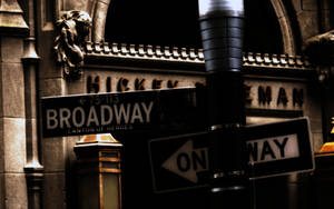 夜晚的 Broadway 街道標誌，石頭建築上有單向箭頭。