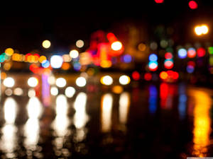 夜間城市燈光在潮濕路面上反射出散景效果