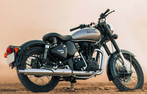 經典 Royal Enfield 電單車停在沙漠地面，背景塵土飛揚。 — 機車 壁紙
