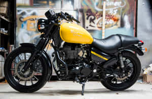 黃黑色 Royal Enfield 電單車停泊在佈滿塗鴉的車庫內。 — 機車 壁紙
