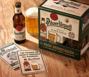 Pilsner Urquell啤酒瓶、玻璃杯和品嚐套裝在木桌上，陽光照射。