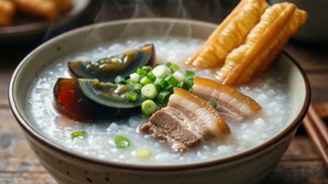 一碗熱騰騰的粥，配有皮蛋、豬肉和油條。