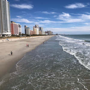 陽光明媚的日子裡，海灘上有海浪和高樓大廈沿著海岸線。