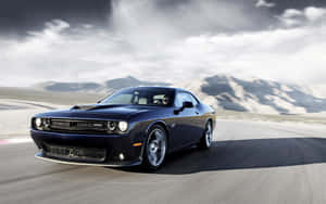 深藍色 Dodge Challenger 在沙漠賽道上奔馳，背景有山脈。