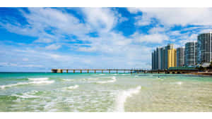 陽光普照的天空下，有碼頭和高樓大廈的海岸沙灘。