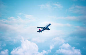 一架英國航空公司的飛機在清澈的藍天中，高高飛過蓬鬆的白雲。