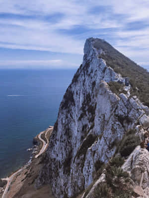 陡峭的岩石懸崖俯瞰海洋，有蜿蜒的海岸公路。 — 岩石 壁紙