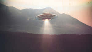 一個發光的UFO懸浮在森林上空，背景是山脈，日落時分。