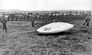 三名身穿軍裝的男子站在草地上一個大型 UFO 附近。
