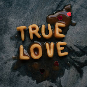 焦糖字母喺深色表面上拼出「true love」，伴隨紅色心形。