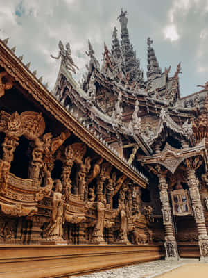 一座華麗的木製寺廟，細節雕刻和雕像，天空多雲。 — 建築 壁紙