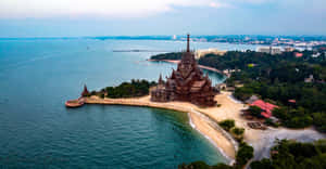 海灘半島上的木製寺廟，背景是海洋和城市 — 海洋 壁紙