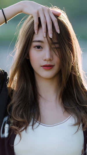 年輕女性，棕色頭髮，在戶外柔和陽光下觸碰額頭。