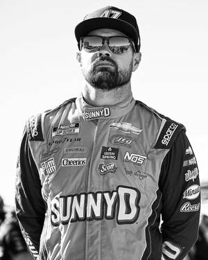 NASCAR車手身穿賽車服同帽，戴住反射人群嘅太陽眼鏡。