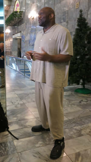 身穿米色休閒服的男士在大理石大堂聖誕樹附近做手勢。 — 運動 壁紙
