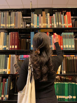 一個捲髮的人在圖書館瀏覽書籍