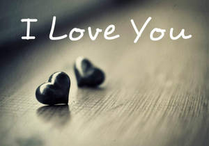 木頭上的兩塊心形石頭，帶有「I Love You」文字。