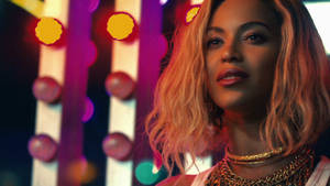 Beyoncé 在夜晚色彩繽紛的霓虹燈下佩戴華麗的金色珠寶。