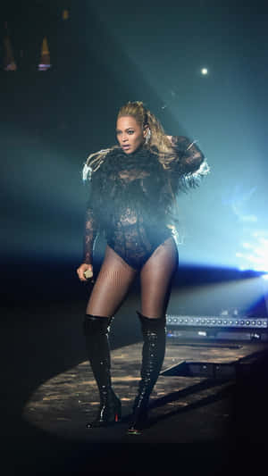 Beyonce 在藍色燈光下身穿黑色蕾絲服裝在舞台上表演。