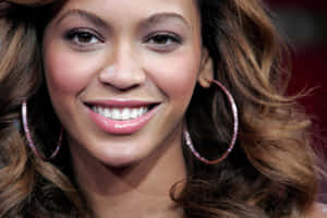 Beyoncé 微笑，戴著大圈形耳環，波浪棕色頭髮。