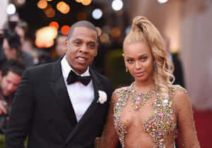Beyoncé 和 Jay-Z 穿著正裝在紅地毯上擺姿勢，背景有攝影師。