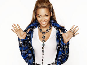 Beyoncé 微笑著雙手張開，身穿藍色格紋外套和個性項鍊。