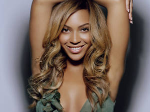 Beyonce 舉起雙臂，溫暖微笑，擺出工作室肖像姿勢。