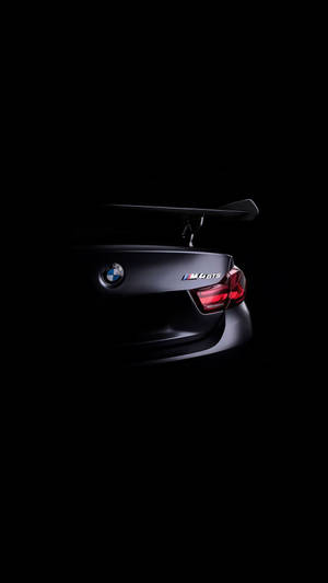 黑色BMW M6 GTS跑車後方，在黑暗的攝影棚環境中帶有發光的紅色尾燈。