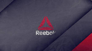 Reebok 標誌位於有紋理的深藍色布料上，帶有紅色對角線條紋。
