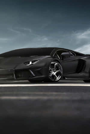 啞光黑色林寶堅尼 Aventador 配碳纖維飾邊，停在黑暗道路上，天空灰色。