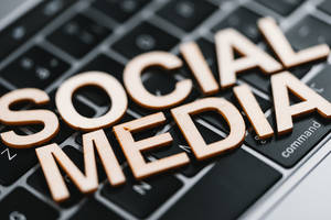 拼出 social media 的木製字母在黑色鍵盤上。