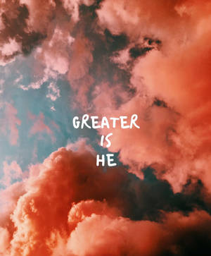 戲劇性的橙色和藍綠色雲彩，帶有白色文字 'GREATER IS HE'。 — Galaxy Z Fold 5 壁紙