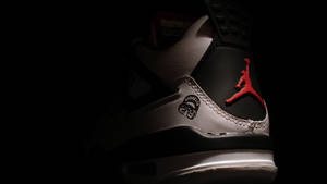 一雙在昏暗光線下帶有紅色標誌的黑白 Jordan 運動鞋。