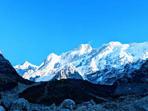 晴朗藍天下的雪山山脈，岩石前景 — 曼達洛人 GIF 壁紙
