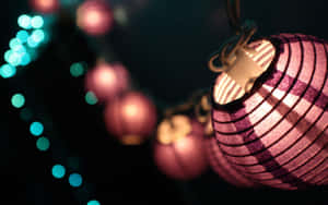 夜間背景中帶有青綠色散景燈光的發光粉紅色燈籠。 — 燈籠 壁紙
