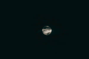 在黑暗的夜空中，月亮被雲層部分遮蓋。