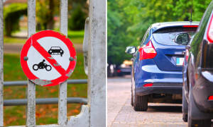 閘門上的禁止汽車或電單車標誌，旁邊停有藍色汽車。