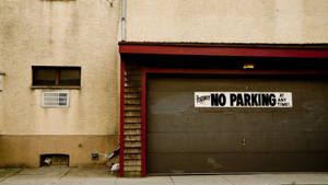 一座米色建築，帶有紅色車庫門和一個「No Parking」標誌。